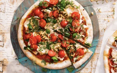 Pizza pikante hummus met tomaat, pijnboompitten en verse kruiden